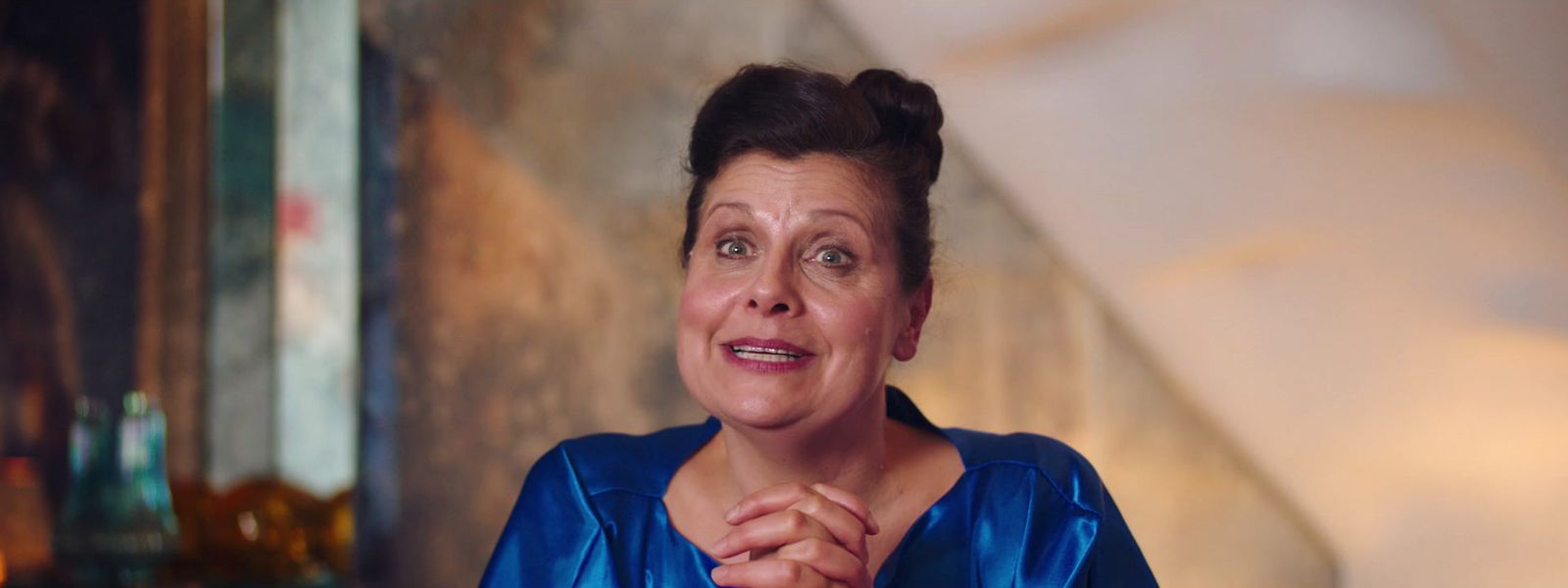 a woman in a blue dress standing in front of a wall