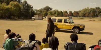 a group of people sitting in front of a yellow car