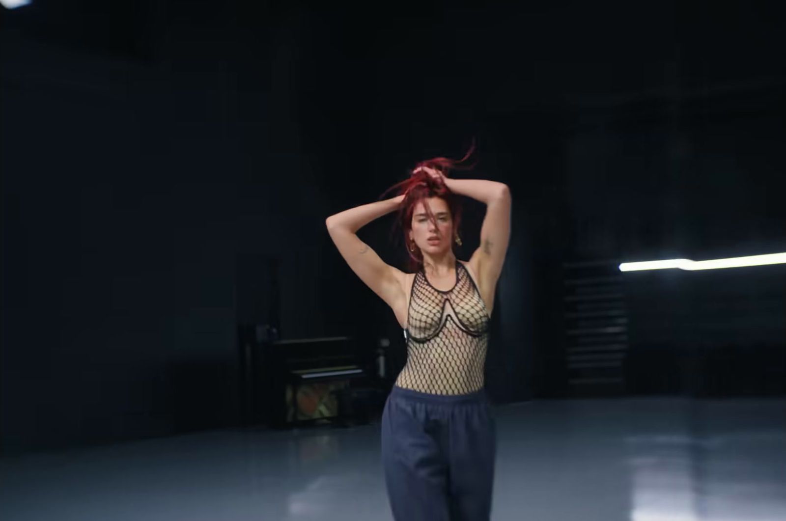 a woman with red hair standing in a dark room