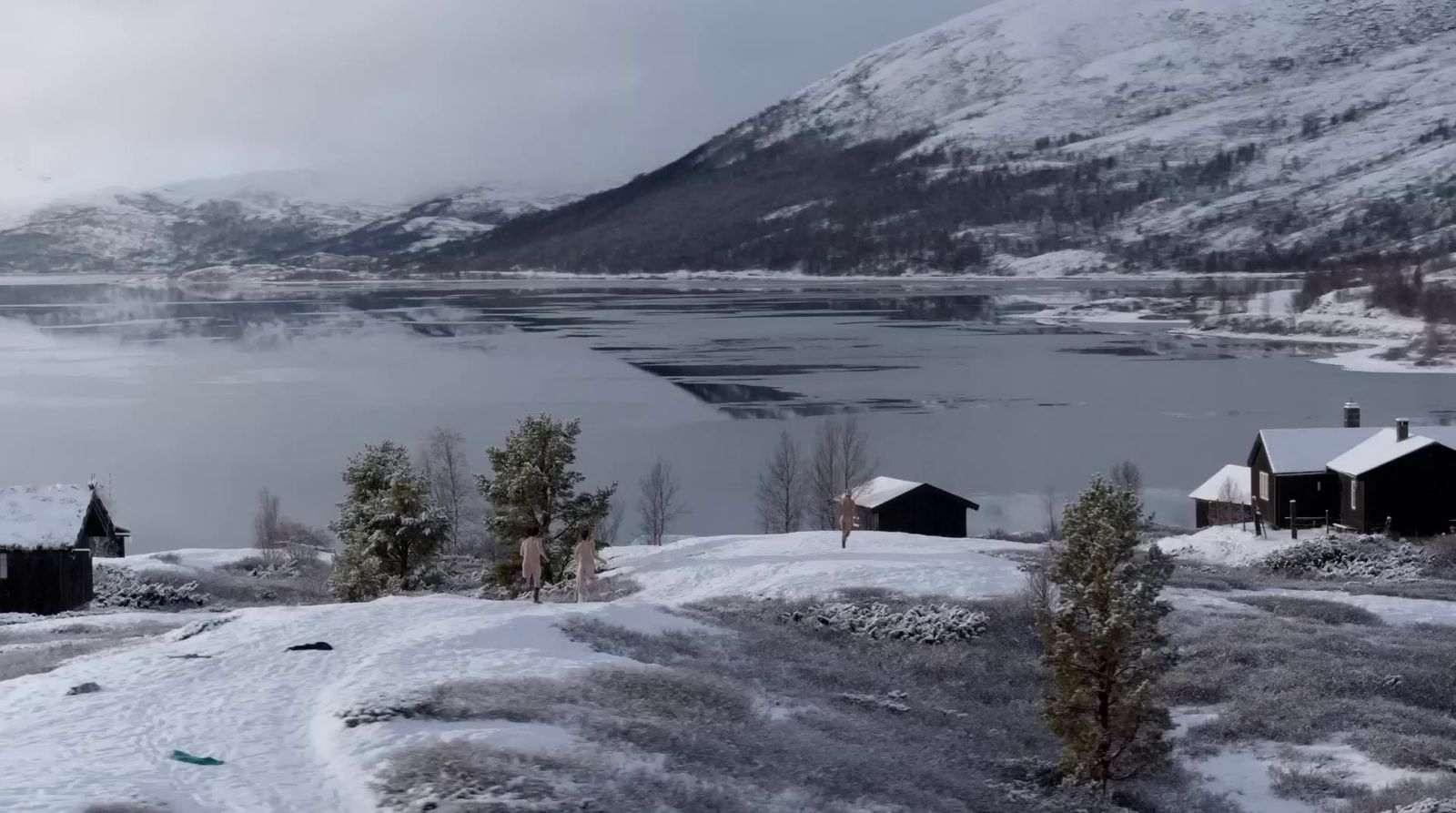 a snowy landscape with a lake and mountains in the background