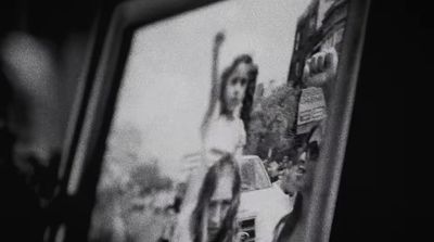 a black and white photo of a woman standing in front of a tv