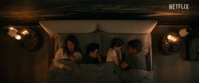 a group of people laying in a bed under a light