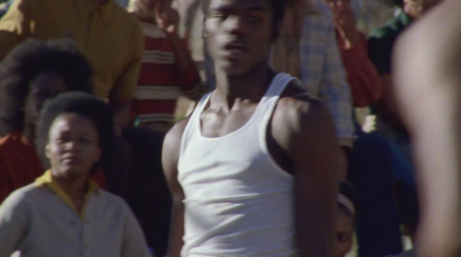 a man in a tank top standing in front of a crowd of people