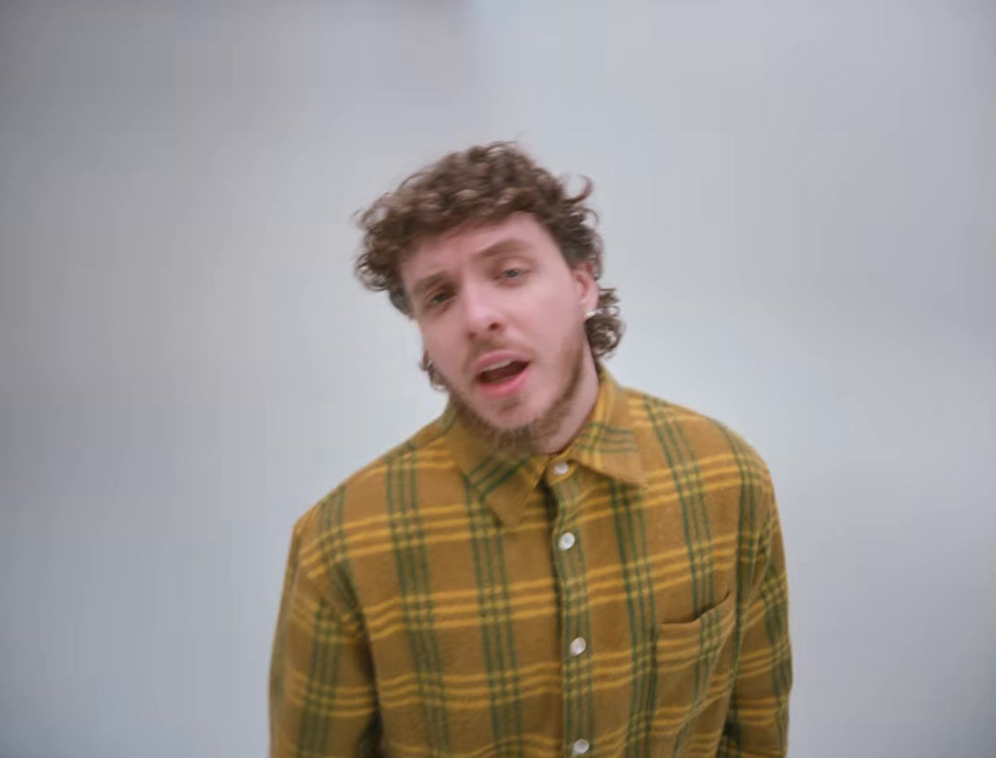 a man with curly hair wearing a yellow shirt