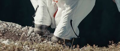 a person in white pants and boots walking up a hill