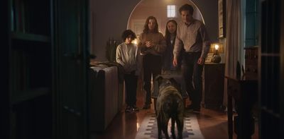 a group of people standing in a living room next to a dog