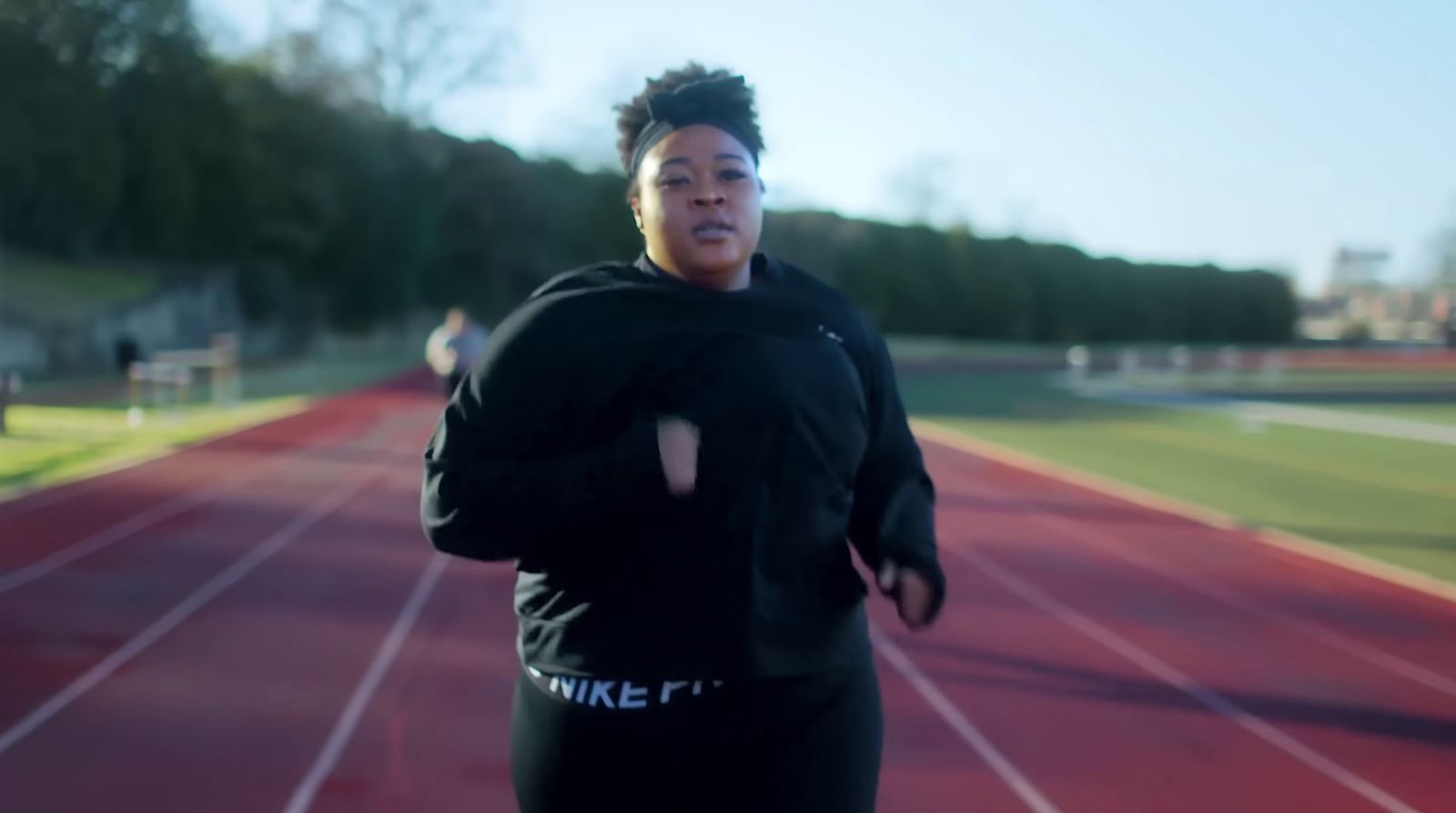 a woman running on a track with trees in the background