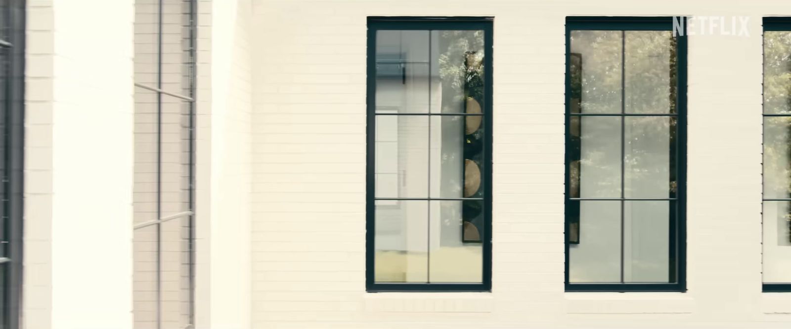 a white building with three windows and a bench in front of it