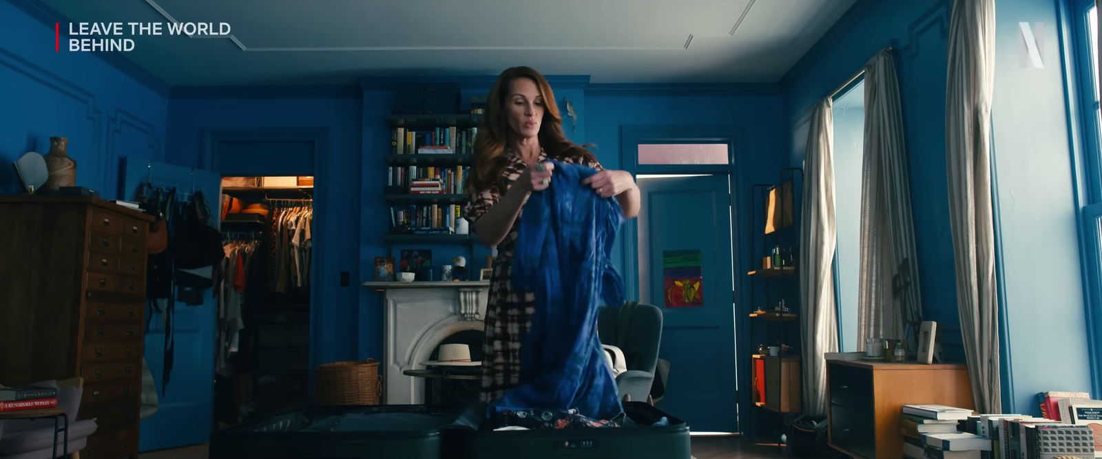 a woman standing in a blue room holding a blue jacket