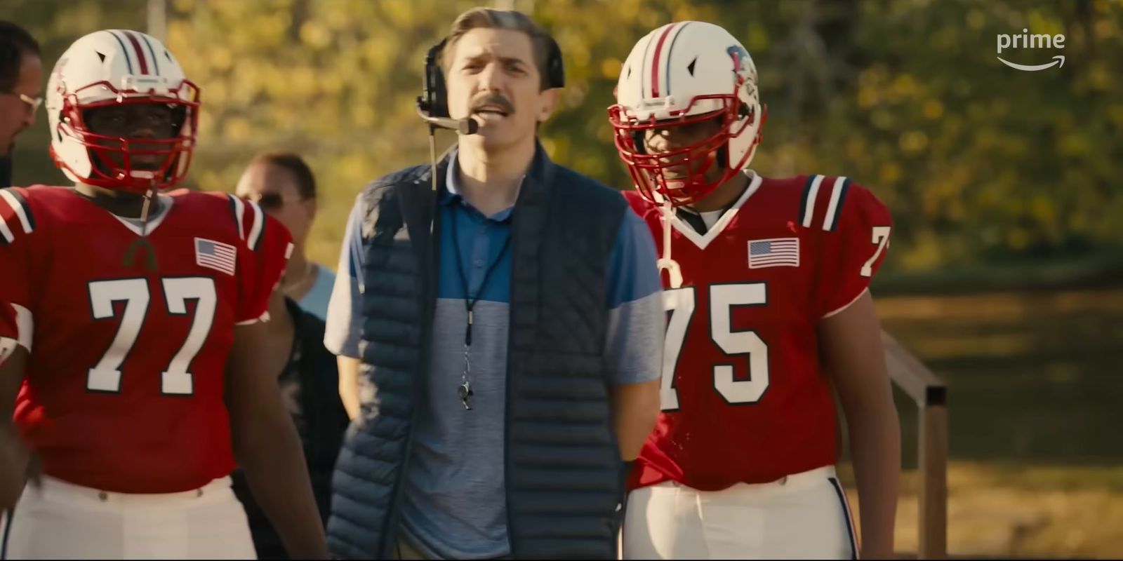 a man standing next to two football players