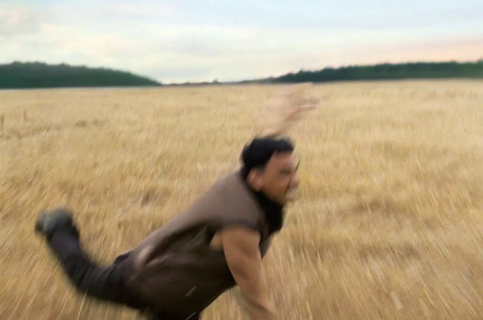 a man running through a field of dry grass