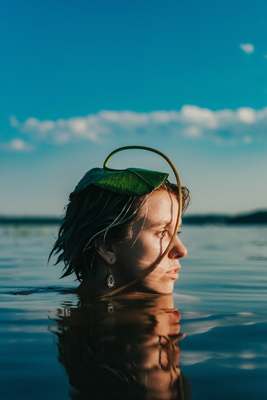 a woman in the water with a green leaf on her head