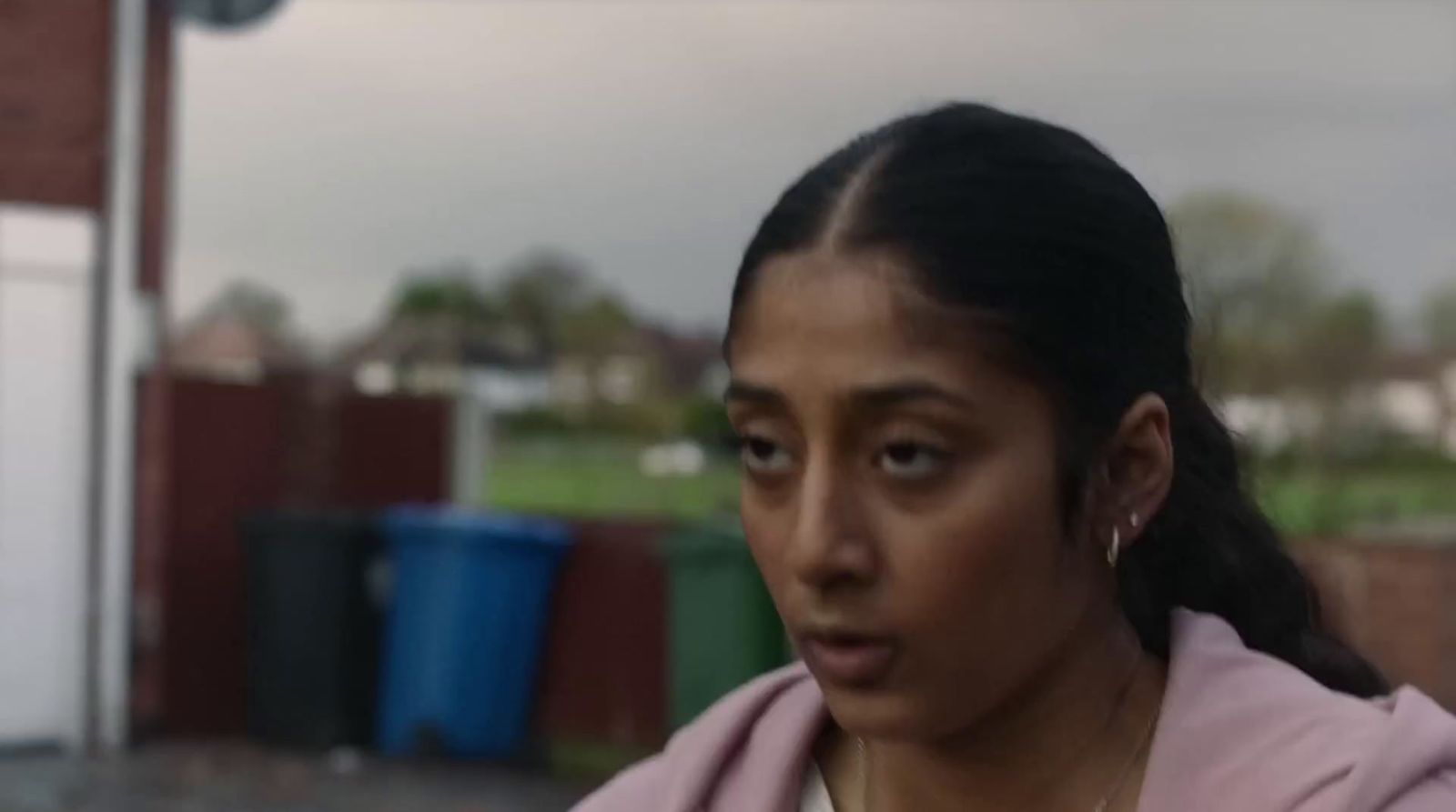 a woman in a pink hoodie looking at the camera