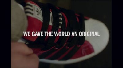 a person holding a pair of sneakers with the words we gave the world an original