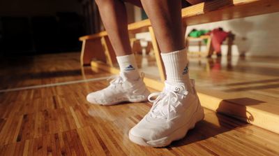 a person sitting on a bench wearing tennis shoes