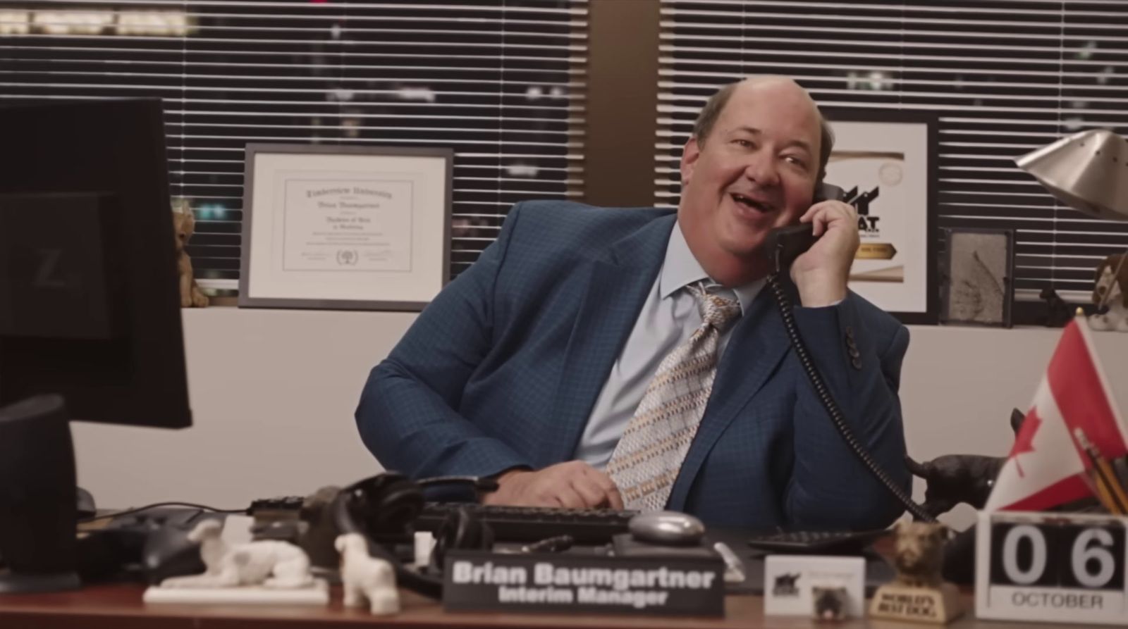 a man sitting at a desk talking on a phone