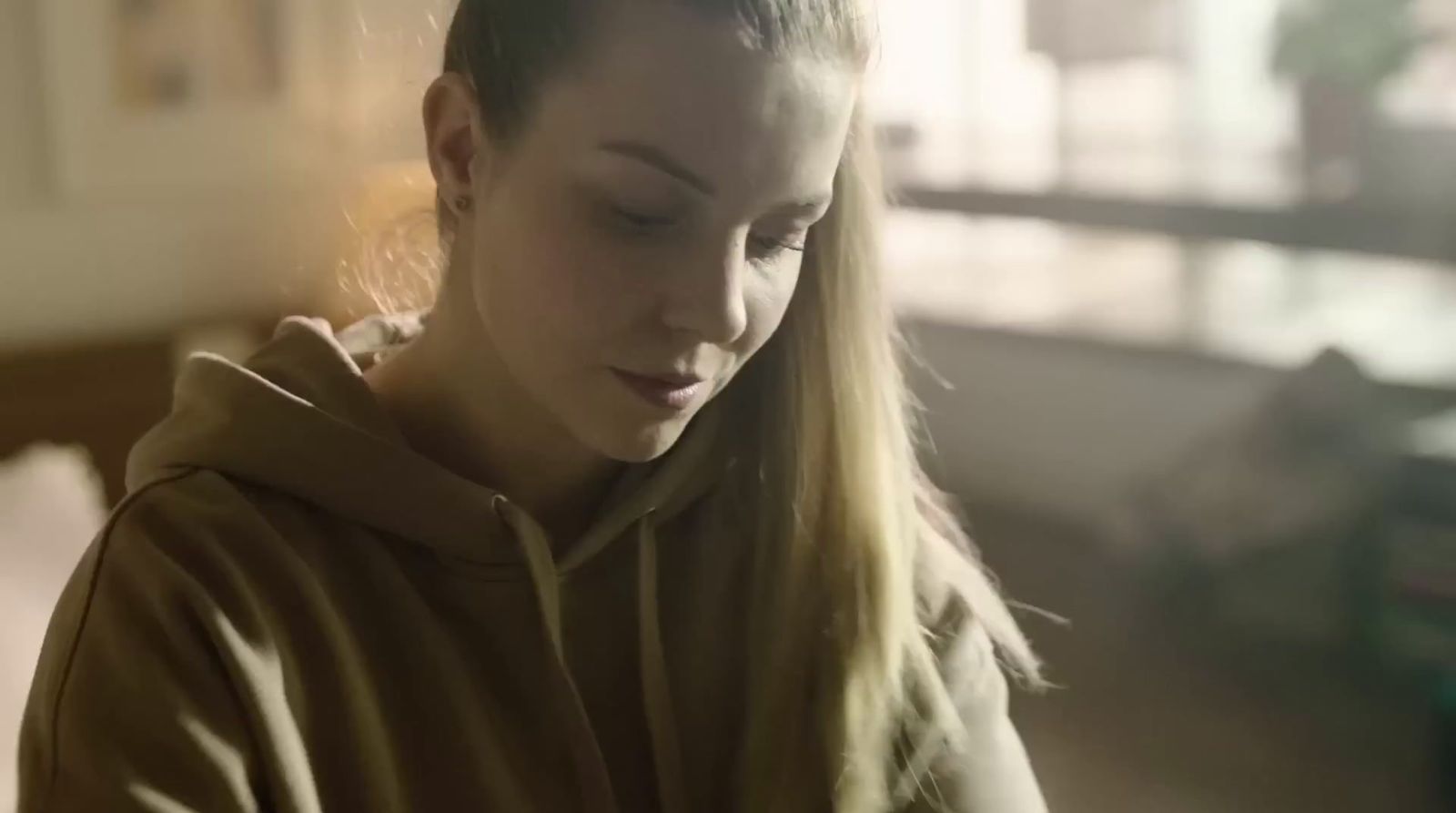 a woman in a brown hoodie looking at her cell phone