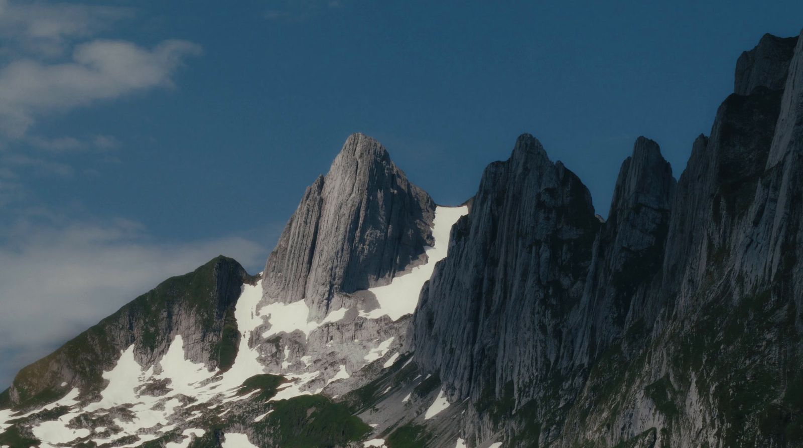 a snow covered mountain with a few clouds in the sky