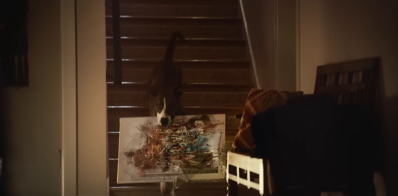 a cat standing on top of a stair case next to a painting