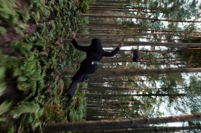 a person in a black hoodie standing in a forest