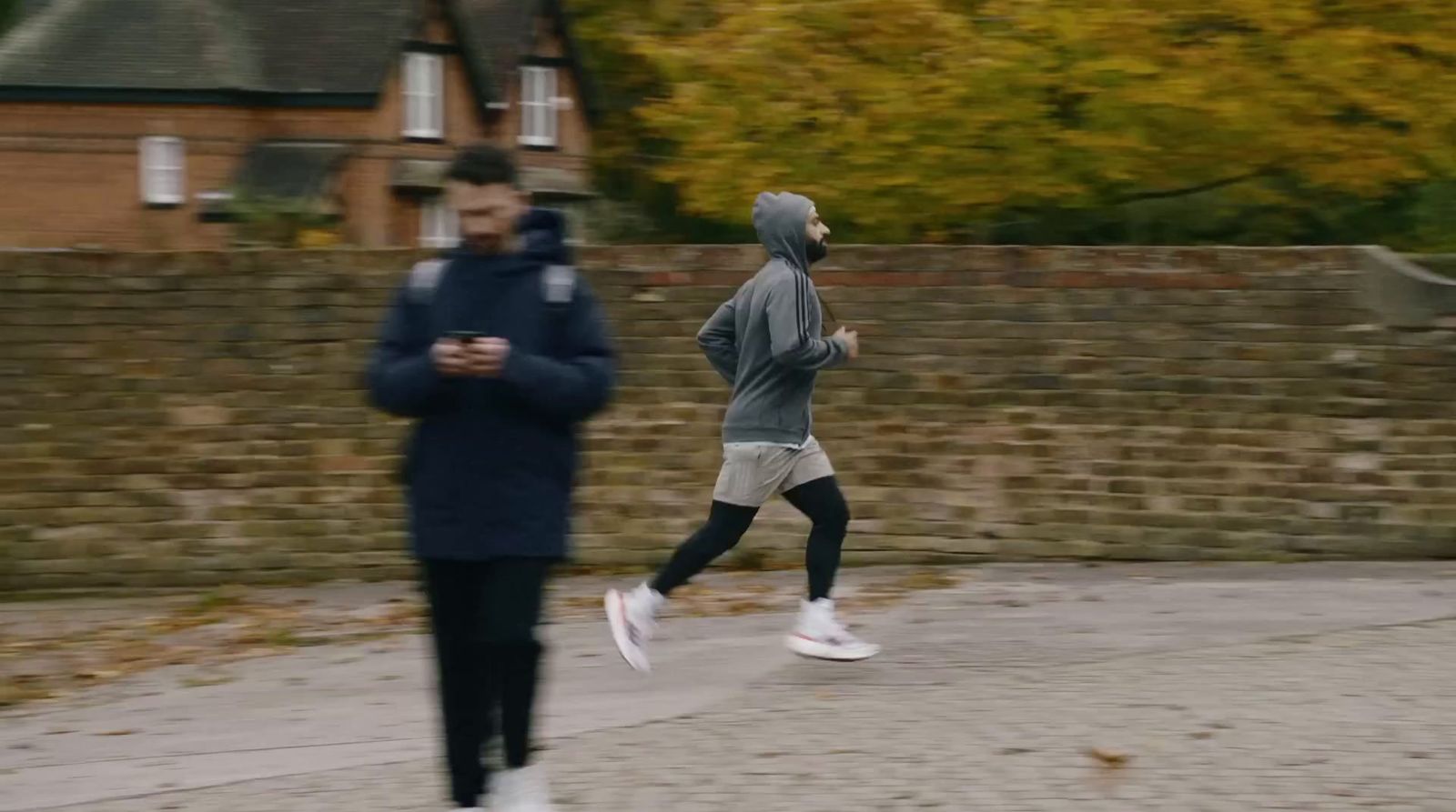 a man running down a street next to a brick wall