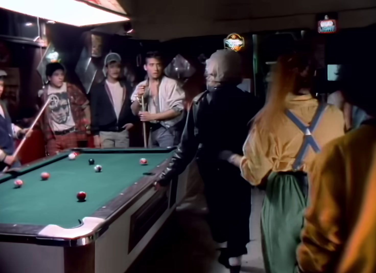 a group of people standing around a pool table