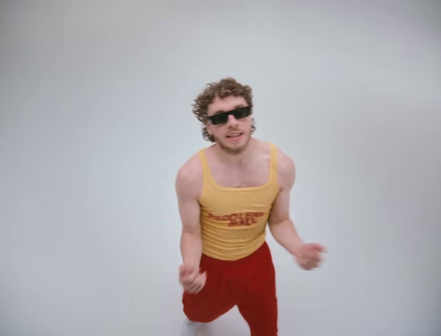 a man in a yellow tank top and red pants