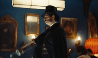 a man with a top hat and a cane in a room