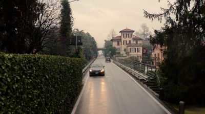 a car driving down a street next to a lush green hedge