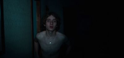 a shirtless man standing in a dark room