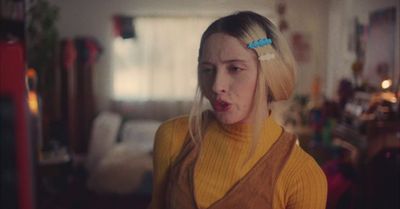 a woman with blonde hair wearing a yellow sweater