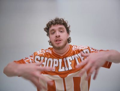 a man with curly hair wearing an orange and white football jersey