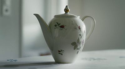 a white tea pot with a flowered design on it