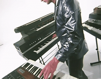 a man in a leather jacket playing a piano