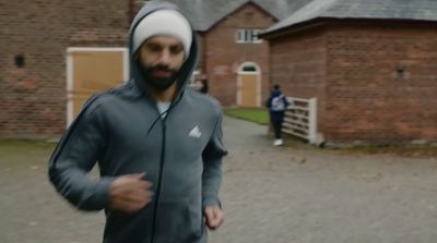 a man wearing a hoodie running in front of a brick building