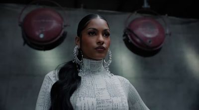 a woman with long black hair wearing large earrings