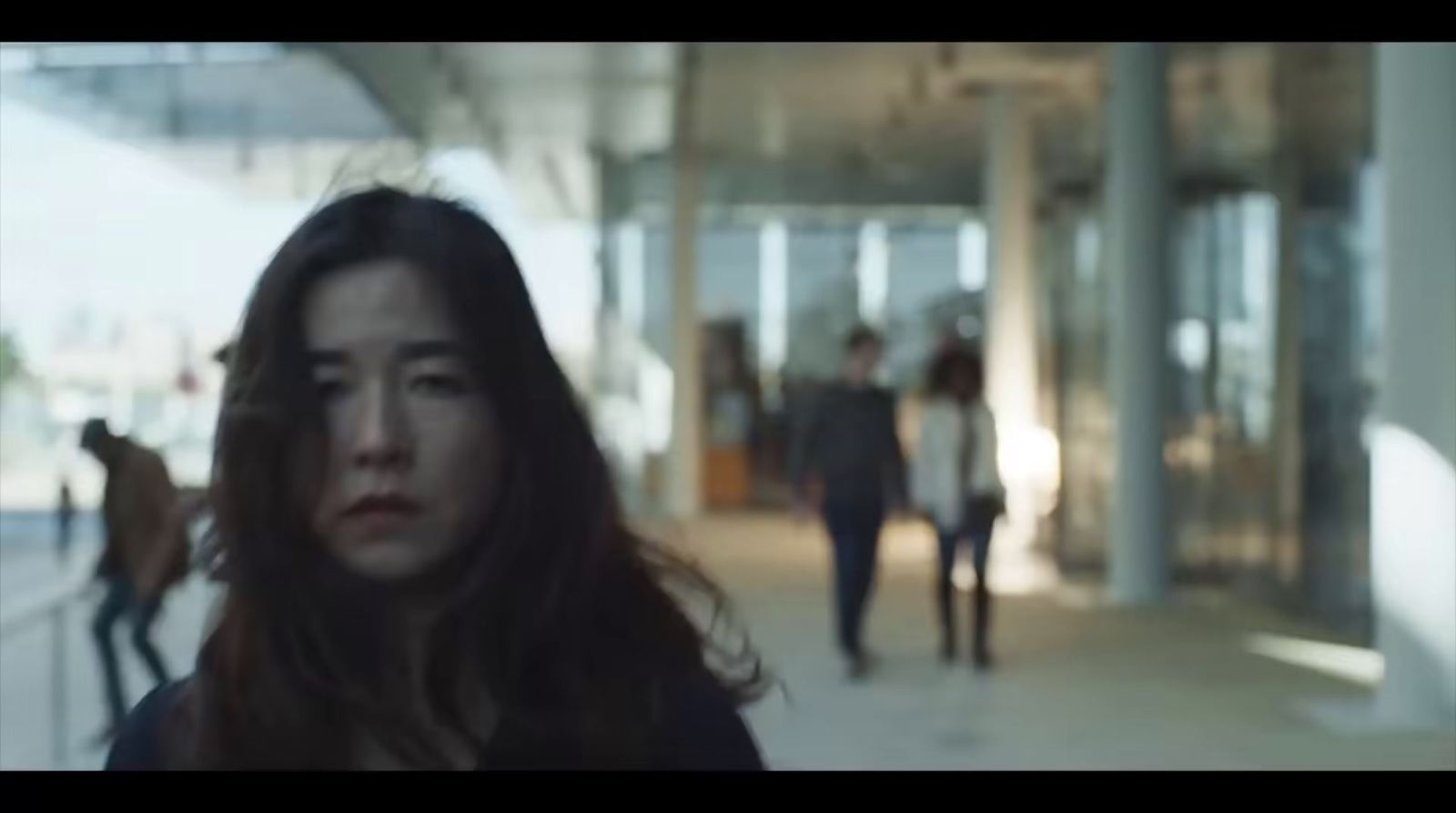 a woman with long hair walking down a hallway