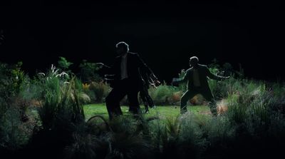 two men in suits are dancing in the grass