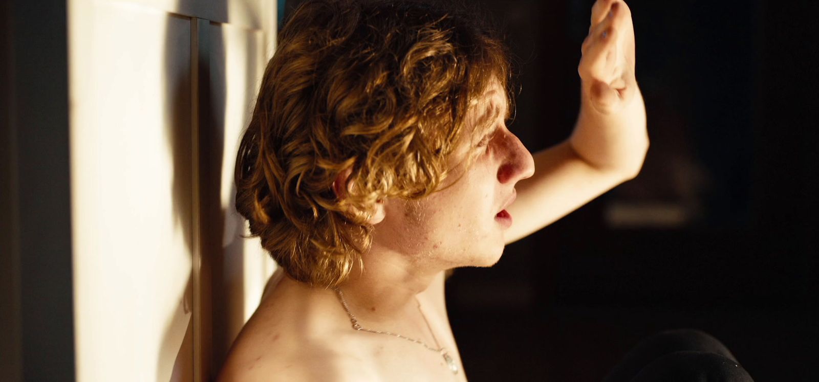 a shirtless young man leaning against a wall