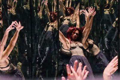 a woman with red hair is dancing in front of a group of people