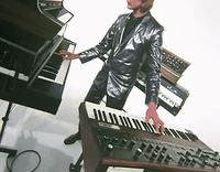 a man standing next to a keyboard in front of a piano