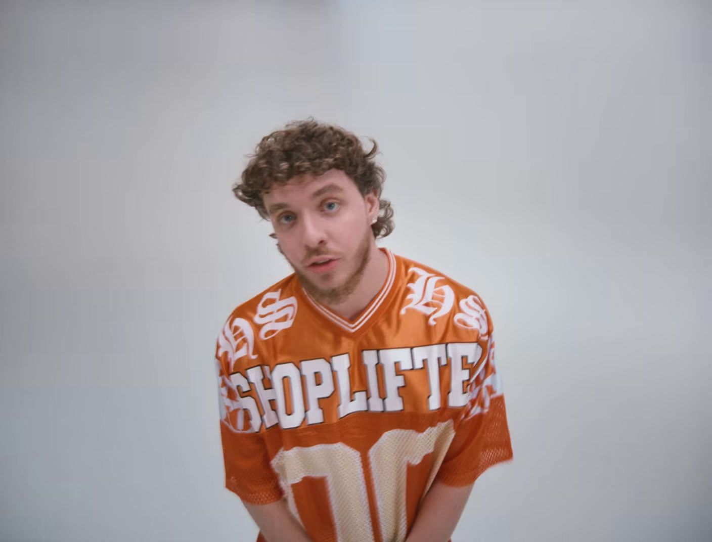 a man in an orange and white shirt holding a baseball bat