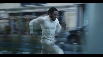 a man in white running in front of a building