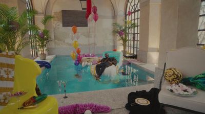 a man sitting in a pool surrounded by balloons