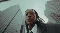 a woman with dreadlocks standing in front of a tall building