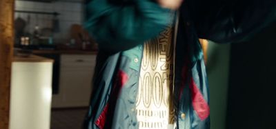 a person standing in a kitchen with a tie around their neck