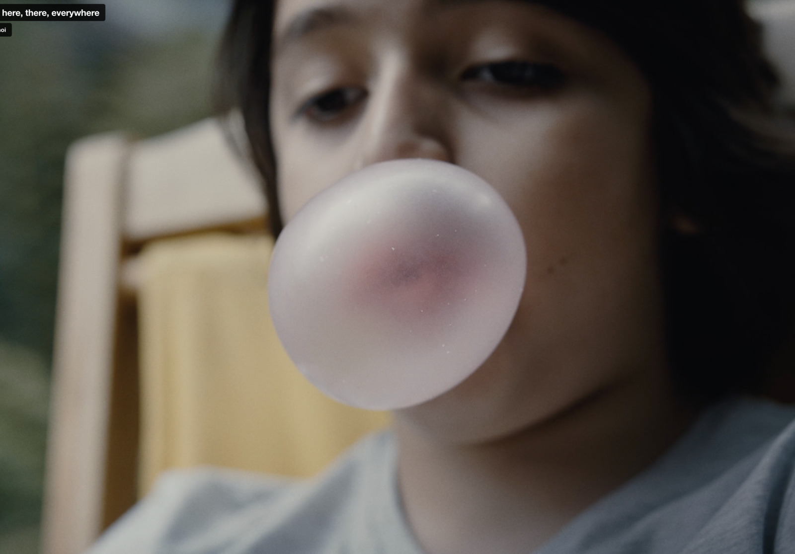 a woman blowing a bubble with a chair in the background