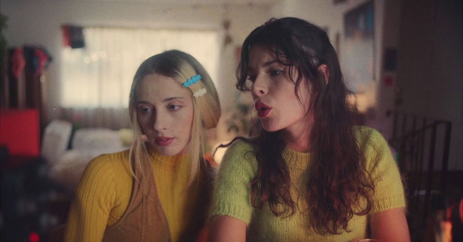 two young women sitting next to each other in a living room