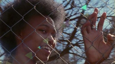 a woman making a peace sign behind a chain link fence