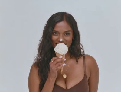 a woman in a brown tank top eating an ice cream cone